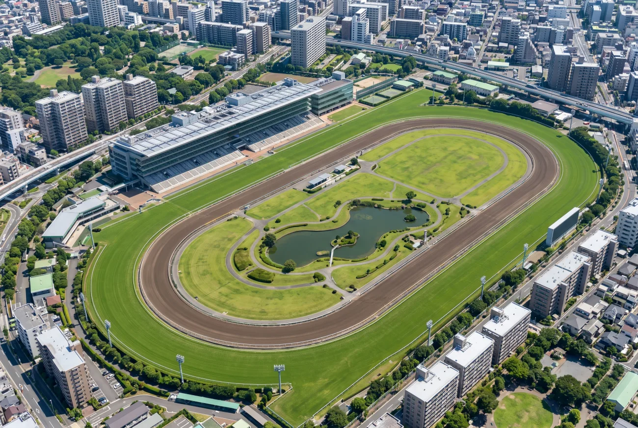 芝・ダートのオーバルとスタンドを備えた大規模な日本の競馬場の空撮