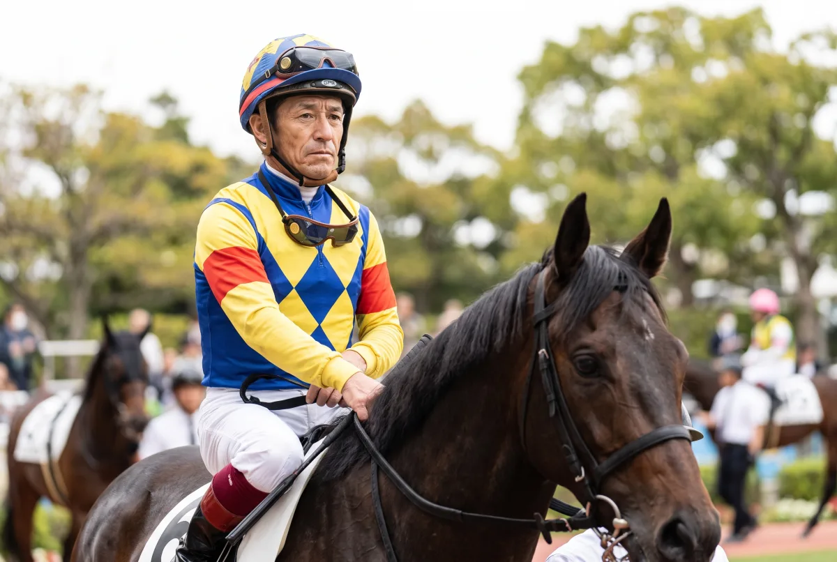 レース前のパドックで馬にまたがる勝負服姿の騎手